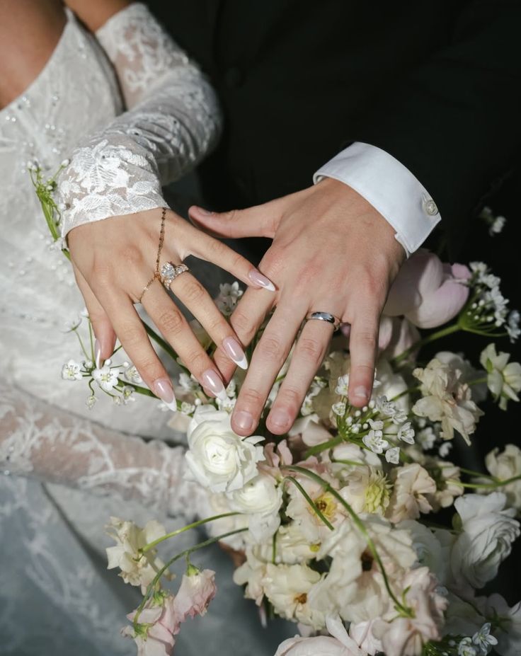 Bride and groom showing wedding rings over a floral bouquet