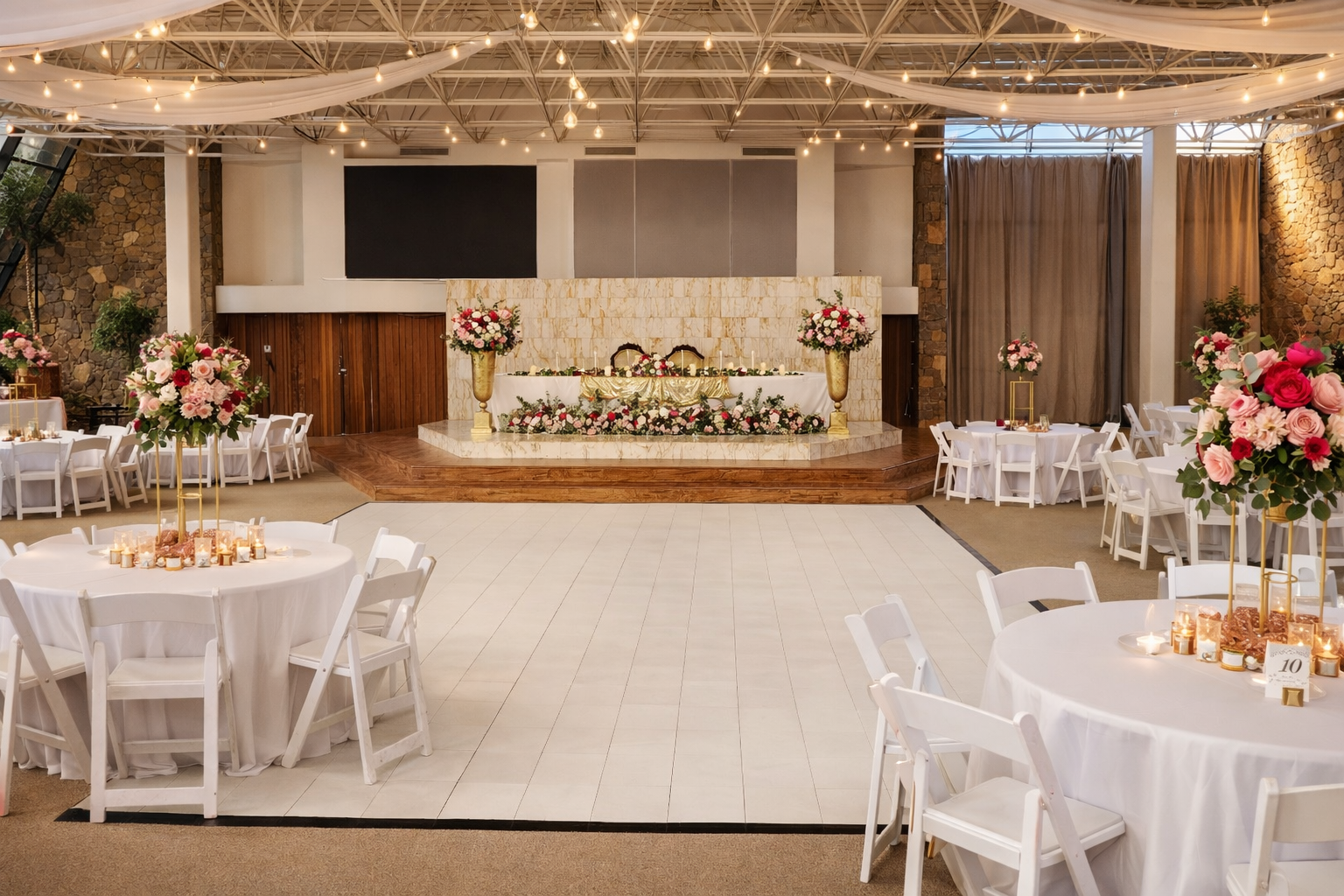 Elegant wedding reception setting at Oasis Grand Hall with floral centerpieces, draped ceiling fabric, and a decorated head table